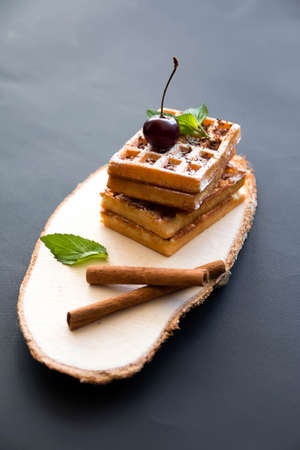 Soft waffles on a black background, with cherries