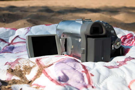 Old video camera on the beach, on a colored bedspread on the sandの写真素材