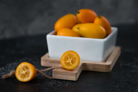 Kumquat fruit in a plate on a black tableの写真素材