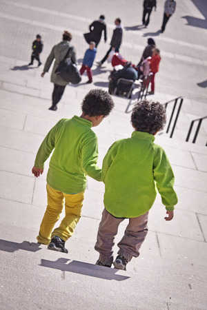 Children in green shirts holding hands in suburban area.のeditorial素材