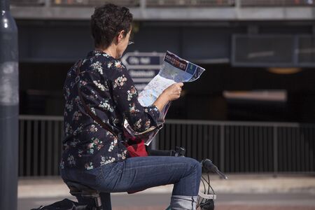 Stockholm, Sweden - August 12, 2016. Woman on a bicycle reading a map.のeditorial素材