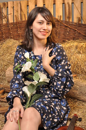 Beautiful young girl smiling with flowers in the hayの写真素材