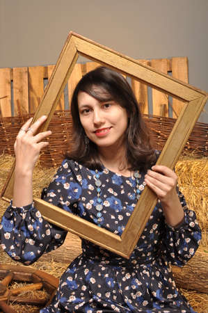 Beautiful young girl with a wooden frame in his hands smilingの写真素材