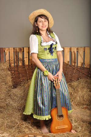 The girl in a dress and a hat with a guitar standing barefootの写真素材