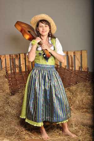 The girl in a dress and a hat with a guitar standing barefootの写真素材
