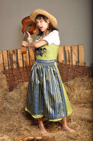 The girl in a dress and a hat with a guitar standing barefootの写真素材
