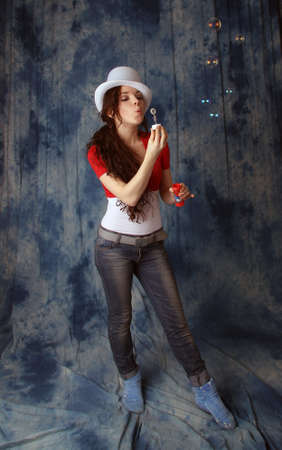 Beautiful young girl with soap bubbles on a blue backgroundの写真素材