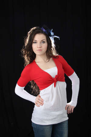Beautiful young girl with long dark hair in a red jacket on a black backgroundの写真素材