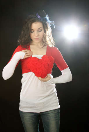 Girl with heart in hand on a black backgroundの写真素材