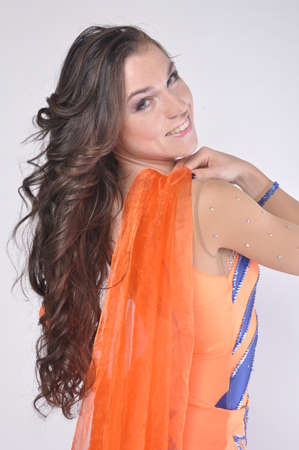 Girl with long dark hair in an orange suit smilingの写真素材