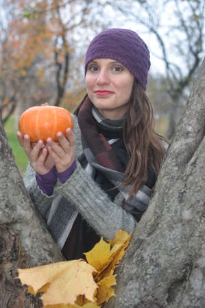 Beautiful girl with a pumpkin in hands smilingの写真素材