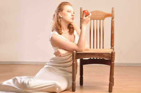 A girl sitting on the floor near the chair with appleの写真素材