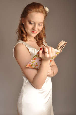 red-haired girl with a book in their hands reading a bookの写真素材