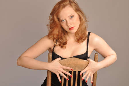 Portrait of a red-haired beauty sitting on a chairの写真素材