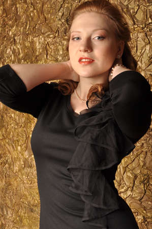girl with red hair in a black dress with his hands behind his headの写真素材