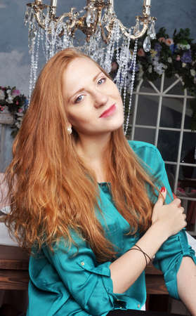 Beautiful red-haired girl in a green blouseの写真素材
