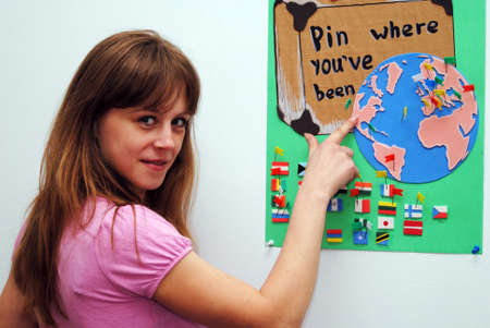 A young girl standing near a world map smilingの写真素材
