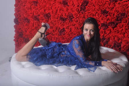 Girl in blue openwork dress sitting on white sofaの写真素材