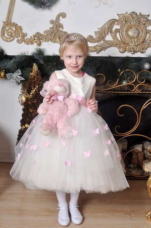 Little girl in a white dress with a toy in handsの写真素材