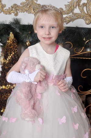 Little girl in a white dress with a toy in handsの写真素材