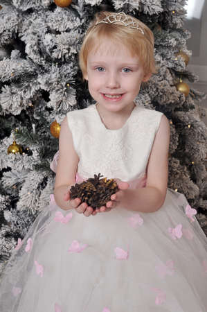 Little girl in white dress with cones in handsの写真素材