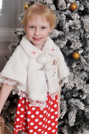 Little beautiful girl in a dress near a Christmas treeの写真素材