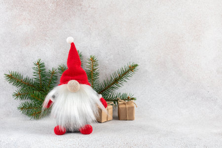 Xmas dwarf in red hat with fir branch holiday card on light winter backgroundの写真素材