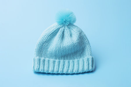 Baby boy knitted warm wool hat cap with pompon on blue background. Handmade conceptの素材