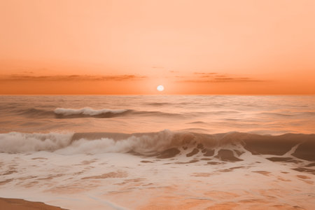 A serene beach at sunset with gentle waves under a soft peach fuzz color sky. Modern trendy tone hue shadeの素材