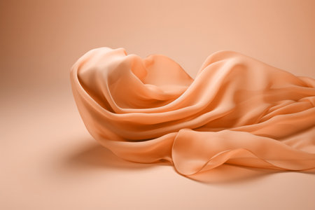 A flowing peach fuzz color silk satin fabric on soft minimal background. Modern trendy tone hue shadeの素材