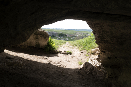 Underground entrance to a cave to the Crimea Russia. Insufficient illumination, rocks, trees, waterの写真素材