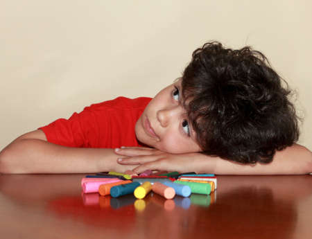 Little artist is resting in front of figure made of colored crayonsの写真素材