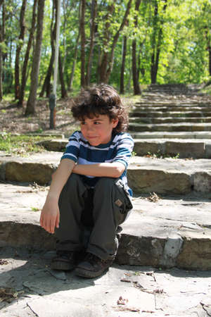 Beautiful smiling boy sitting resting on stone staircaseの写真素材