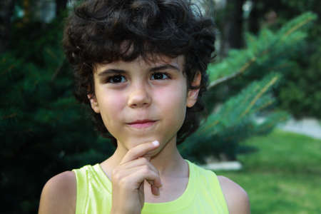 Portrait of a curly little boy in the summer park
