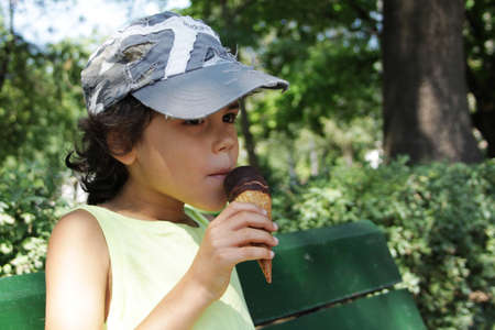 A charming boy eating an ice cream in the park