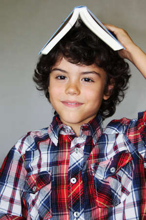 A playful boy with a book on his head, isolated