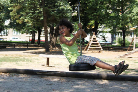 A happy boy on a swing of car tire in the parkの写真素材