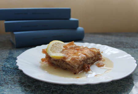 Still life with piece of turkish dessert(baklava) and pile of booksの写真素材