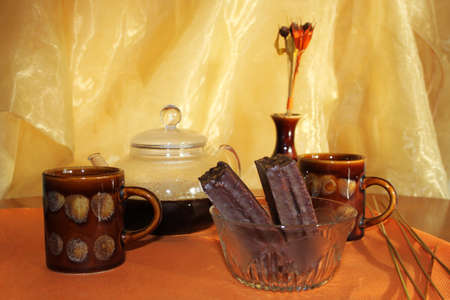 Still life with coffee kettle, ceramic cup and bowl with candies on orange clothの写真素材