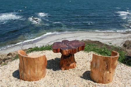 Romantic view at the beach with two wooden chairs and table