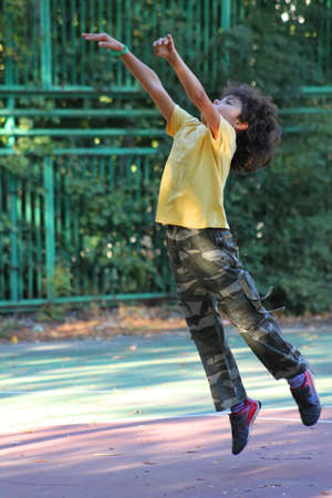 Little boy is jumping on a basketball field