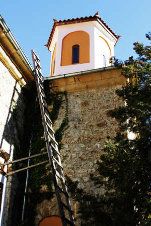 Church tower of old monastery with wooden ladder up to the wall