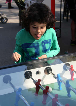 Curly cute boy is playing foosball in the parkの写真素材