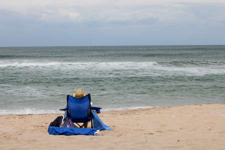 Man sits on the beach watching the sea waves, no faceの写真素材