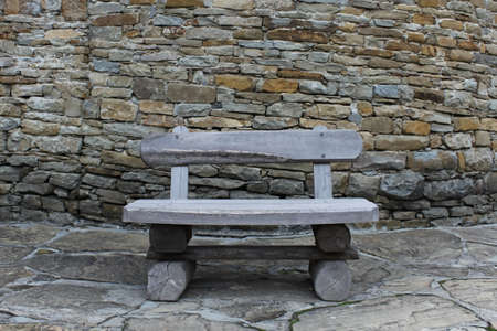 Wooden bench in front of  stone wallの写真素材