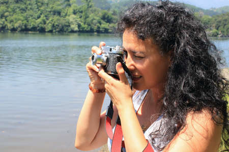 Outdoor picture of a young woman with an old camera