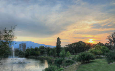 A colorful sunset over the city lake with buildings in the distanceのeditorial素材