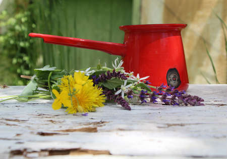 Still life in a rural garden with books, wild flowers, a jug and a cup of coffee on a vintage tableの写真素材