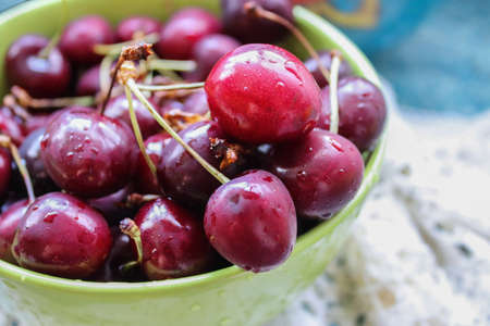 Closeup picture of a green bowl of fresh delicious red cherries