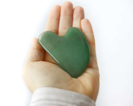 Jade Gree Gua sha jade massage tool in woman's hands. Spa Toolの写真素材